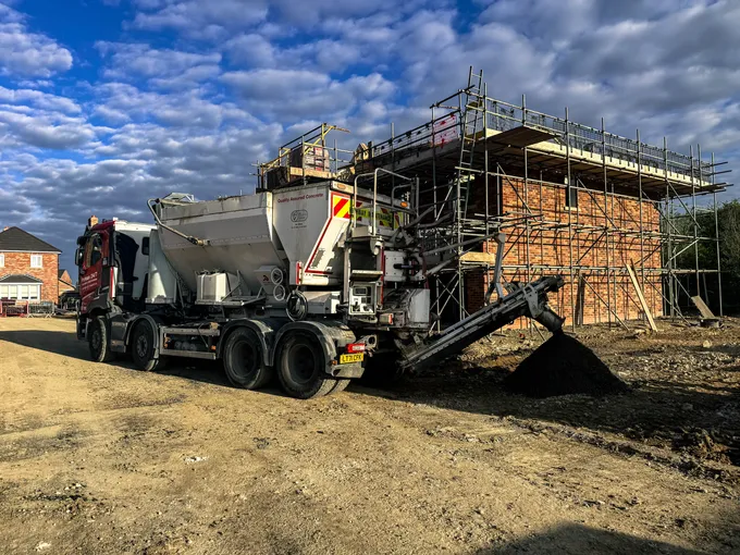 Procon mixer on a scaffolded new-build housing site under blue sky